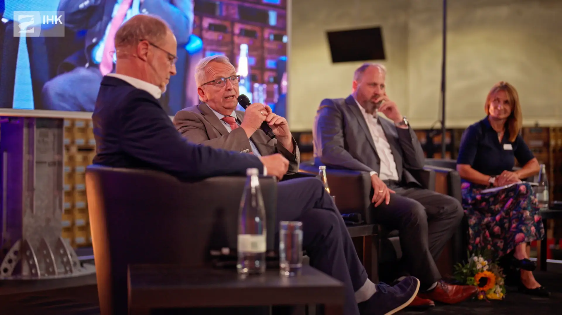 Till Backhaus und weitere Teilnehmer in einer Podiumsdiskussion beim Jahresempfang der IHK zu Rostock 2024, professionell fotografiert auf einer Bühne mit moderner Beleuchtung.