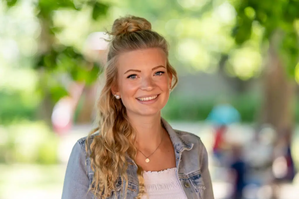 Junge Frau mit lockigem Haar lächelt in die Kamera – professionelle Portraitfotografie von Yourfilms.