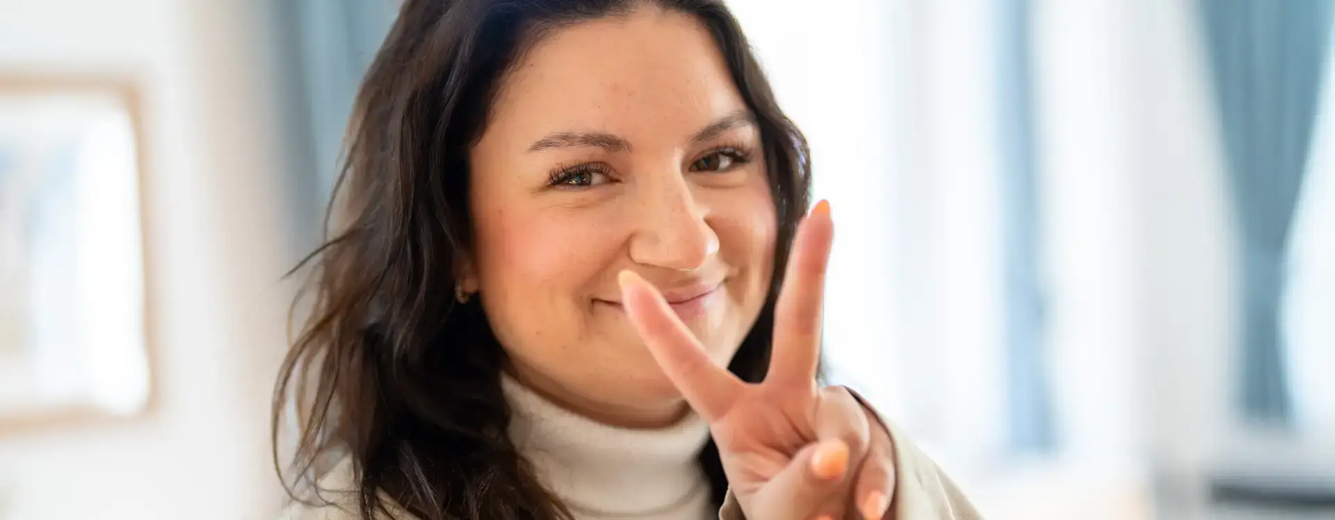 Junge Frau lächelt in die Kamera und zeigt das Peace-Zeichen – professionelle Portraitfotografie von Yourfilms.