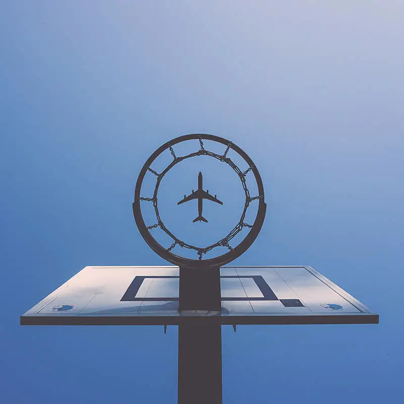 Ein modernes Basketballbrett mit einem Ring, der ein Flugzeug darstellt, vor blauem Himmel. Das Bild symbolisiert Kreativität, Innovation und grenzenlose Möglichkeiten.