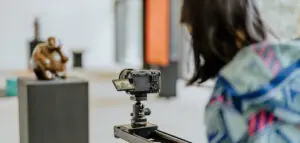 Eine Kamerafrau filmt eine Skulptur mit einer professionellen Kamera auf einem Slider in einer Ausstellung.