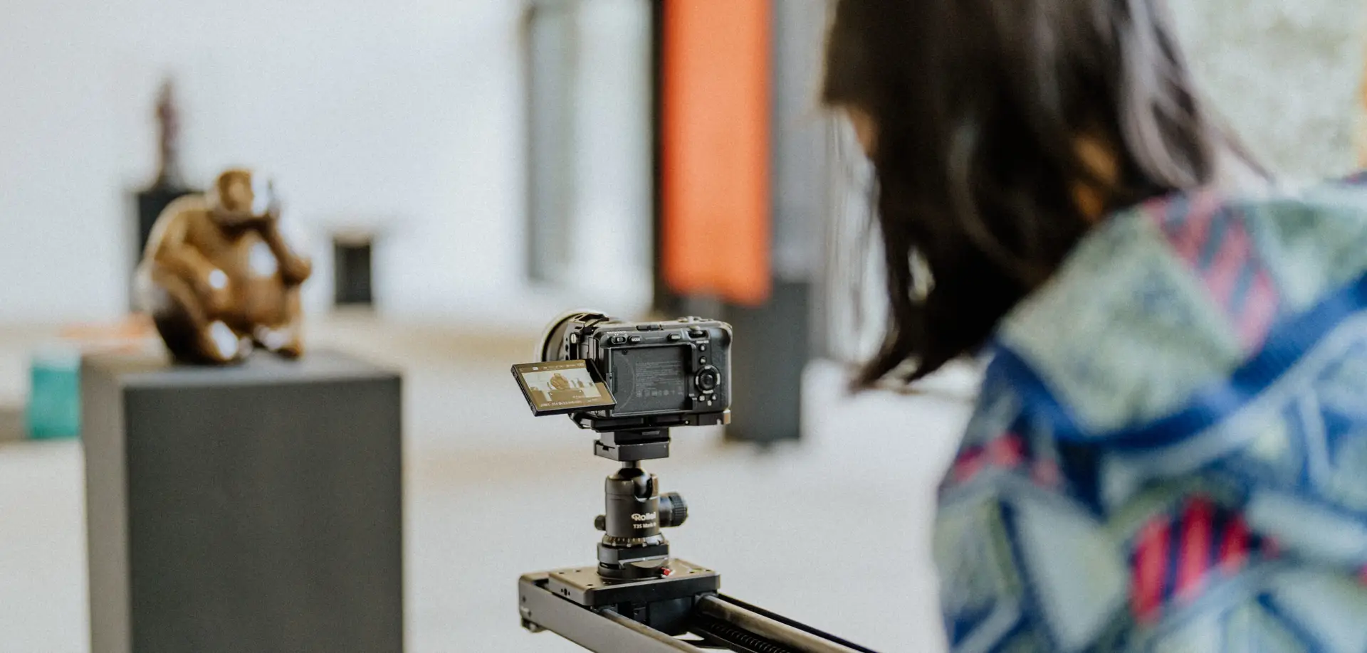 Eine Kamerafrau filmt eine Skulptur mit einer professionellen Kamera auf einem Slider in einer Ausstellung.