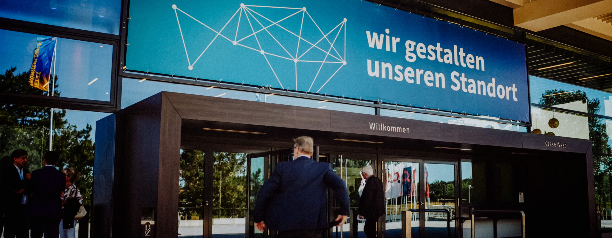 Teilnehmer betreten den Veranstaltungsort des Jahresempfangs der IHK zu Rostock 2025 unter dem Banner „Wir gestalten unseren Standort“