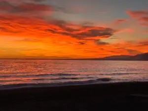 Sonnenuntergang über dem Meer mit orangefarbenem Himmel und ruhiger Wasseroberfläche