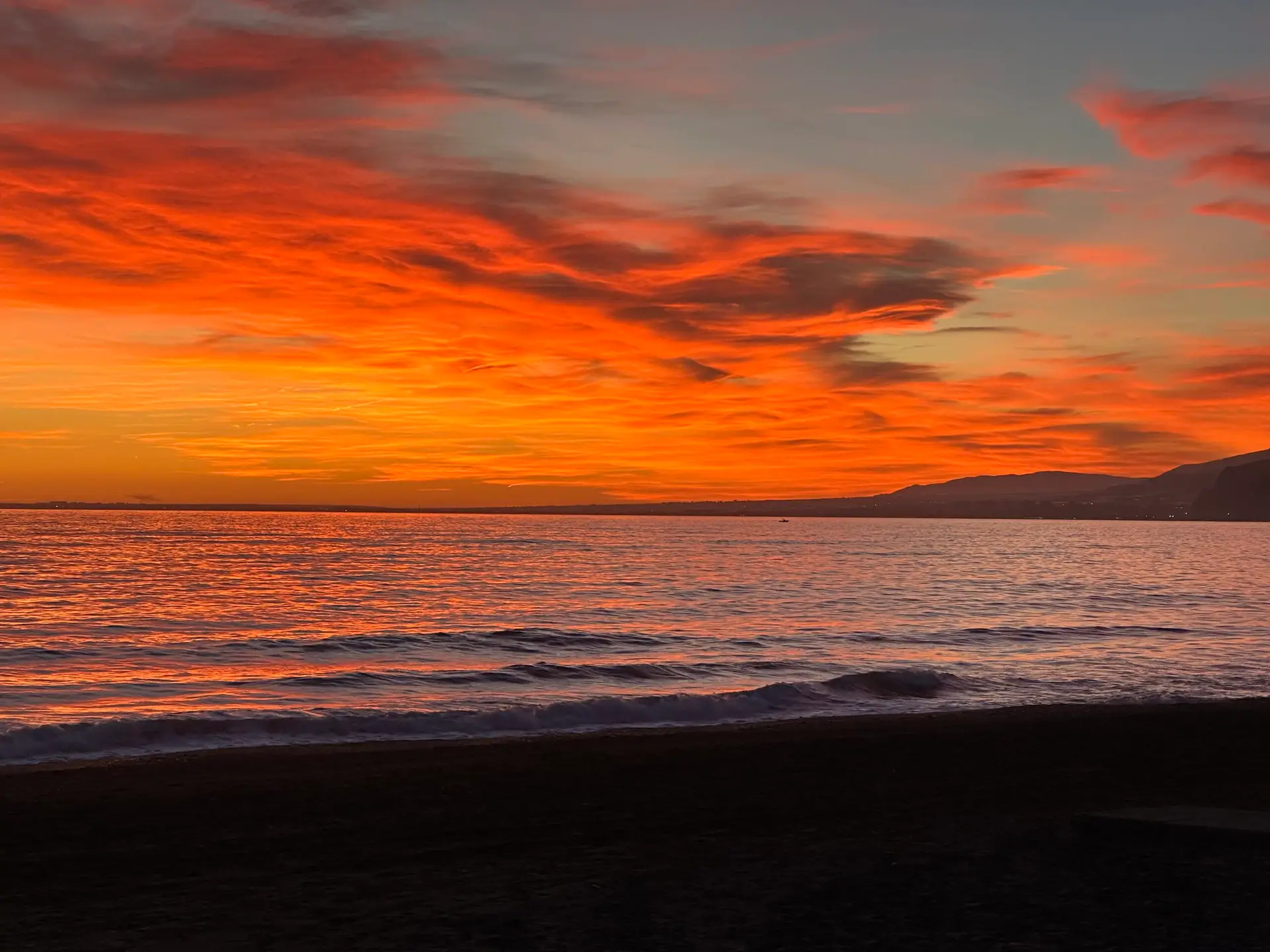 Sonnenuntergang über dem Meer mit orangefarbenem Himmel und ruhiger Wasseroberfläche