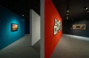 Ausstellungsraum der Ausstellung „Heiter bis wolkig“ im Barlach Museum am Inselsee in Güstrow mit farbigen Wänden und Kunstwerken.