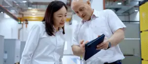Zwei Fachkräfte in einer Industriehalle betrachten ein Tablet zur Planung von Video Marketing für Unternehmen